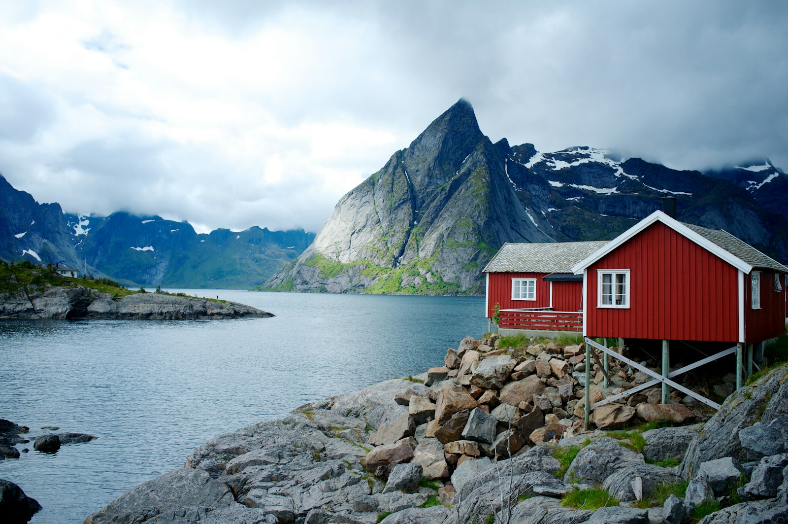 Rote Fischerhäuser am blauen Fjord vor den Bergen von Hamnøy auf den Lofoten